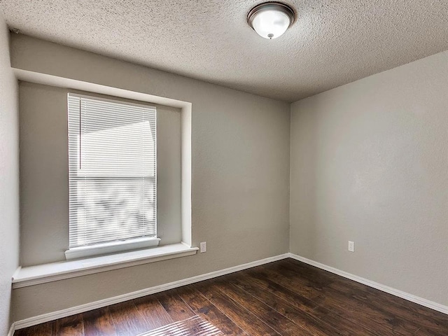 unfurnished room with dark wood-type flooring, baseboards, and a textured ceiling