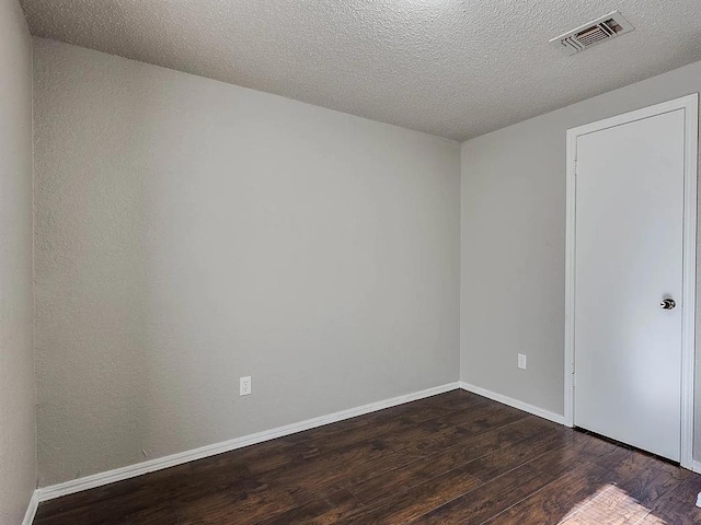 empty room featuring dark wood finished floors, baseboards, and a textured ceiling