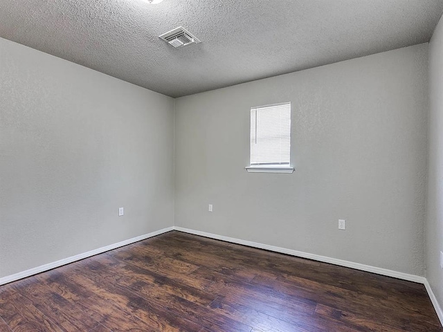 spare room with dark wood-style floors, baseboards, and a textured ceiling
