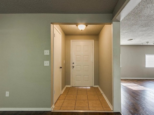 tiled entryway featuring baseboards and a textured ceiling