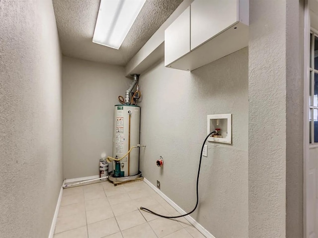 washroom featuring gas water heater, cabinet space, hookup for a washing machine, a textured wall, and light tile patterned floors