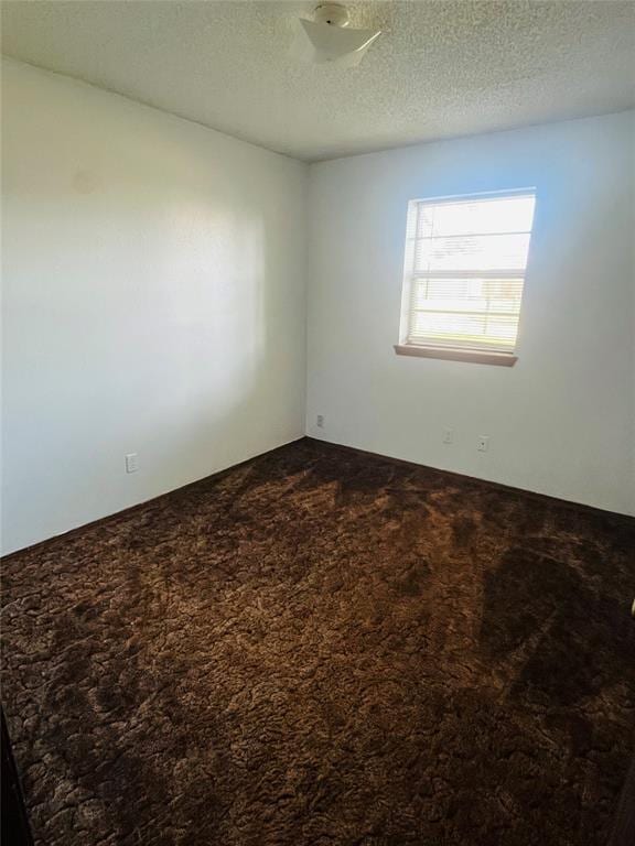 2217 7th St, Prague, OK 74864 - unfurnished room featuring dark carpet and a textured ceiling