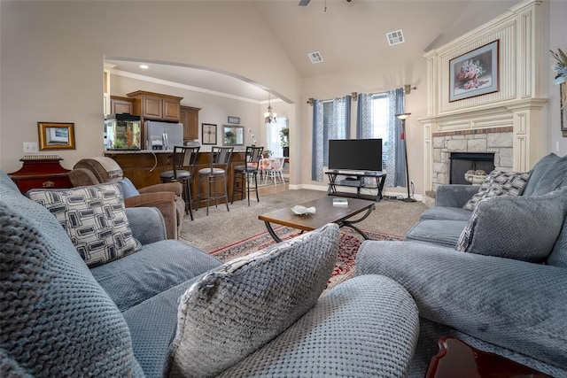 708 Carol Ann Pl, Moore, OK 73160 - living room with arched walkways, light colored carpet, high vaulted ceiling, ceiling fan, and a fireplace