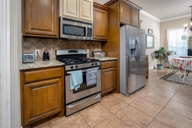 708 Carol Ann Pl, Moore, OK 73160 - kitchen featuring appliances with stainless steel finishes, decorative backsplash, light tile patterned floors, a chandelier, and brown cabinets