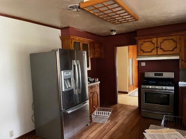 306 W Comanche St, Lindsay, OK 73052 - kitchen with appliances with stainless steel finishes, under cabinet range hood, dark wood finished floors, baseboards, and light countertops
