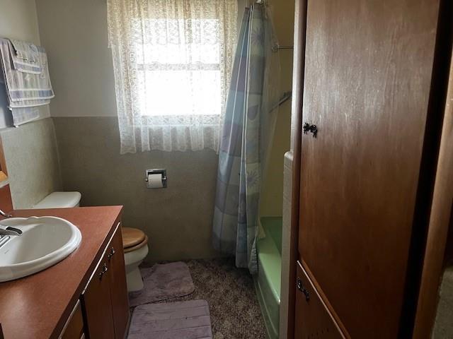 306 W Comanche St, Lindsay, OK 73052 - bathroom with toilet, vanity, and shower / bath combination with curtain