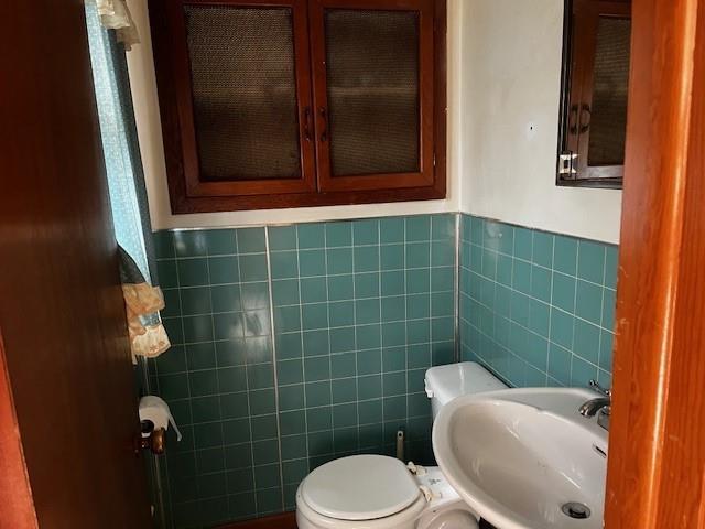 306 W Comanche St, Lindsay, OK 73052 - bathroom with tile walls, a sink, toilet, and wainscoting
