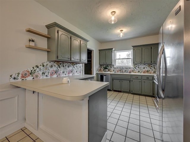 6401 Saddleback Dr, Oklahoma City, OK 73150 - kitchen featuring stainless steel appliances, a peninsula, a sink, light tile patterned flooring, and decorative backsplash