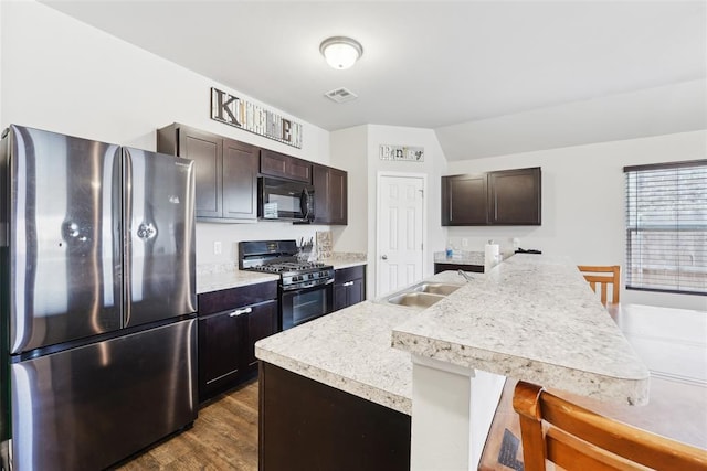 kitchen featuring black appliances, a sink, dark brown cabinetry, and light countertops