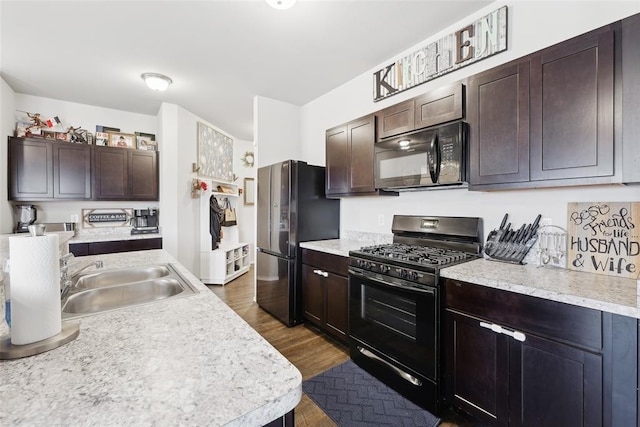 kitchen with black appliances, a sink, light countertops, and dark brown cabinetry