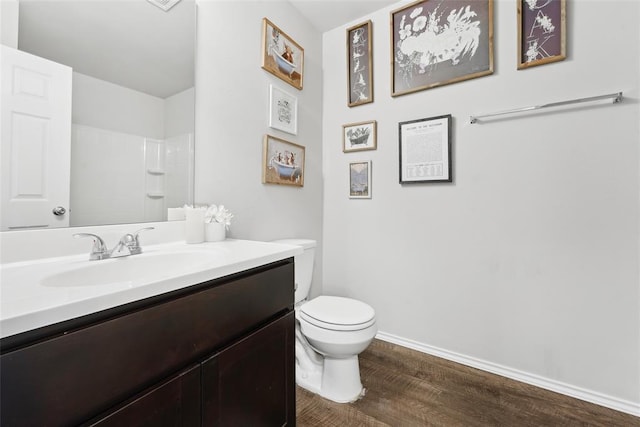full bathroom with wood finished floors, toilet, vanity, baseboards, and a shower