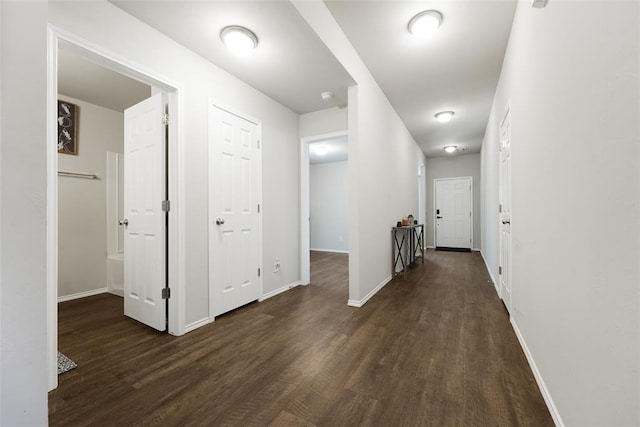 hallway with dark wood finished floors and baseboards