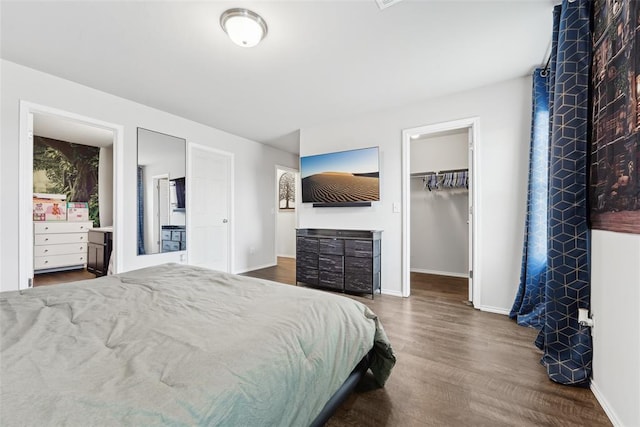 bedroom with a walk in closet, wood finished floors, baseboards, and a closet