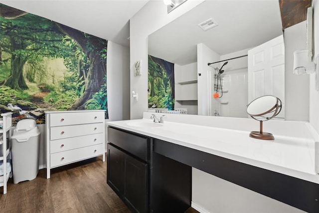 bathroom featuring wood finished floors, a shower, and vanity