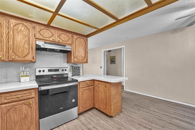 11402 N 1957th Rd, Elk City, OK 73644 - kitchen with under cabinet range hood, electric stove, a peninsula, light wood-type flooring, and light countertops