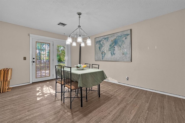 11402 N 1957th Rd, Elk City, OK 73644 - dining space with wood finished floors, a chandelier, baseboards, and a textured ceiling