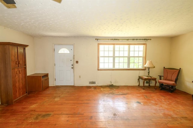 entryway with light wood finished floors and a textured ceiling