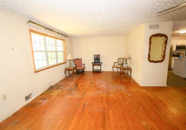 unfurnished room with light wood-type flooring, a textured ceiling, and baseboards