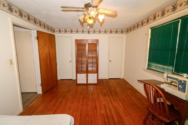 spare room with wood finished floors, a ceiling fan, and baseboards