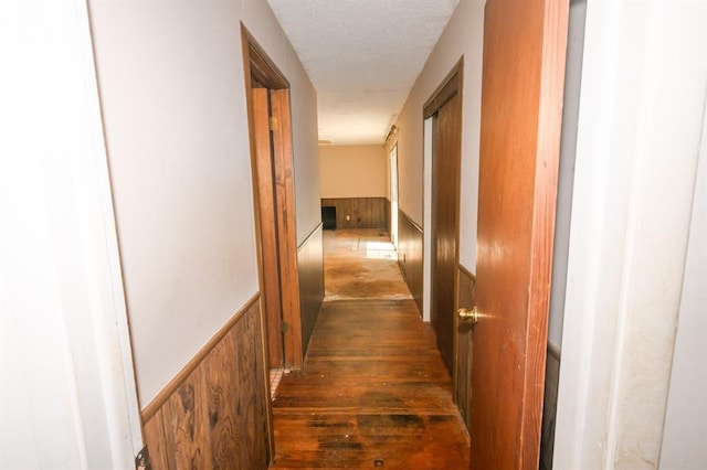 hall with a wainscoted wall and a textured ceiling