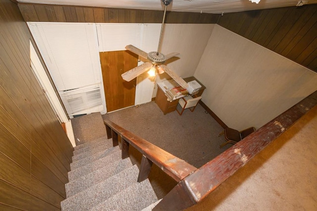 staircase with carpet floors, a ceiling fan, and wooden walls