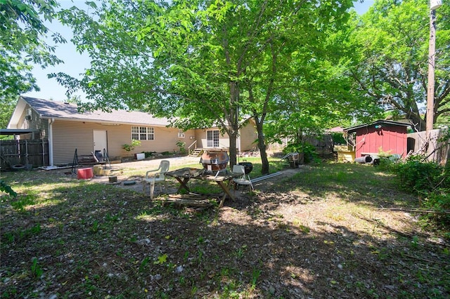 view of yard with a shed, fence, and an outdoor structure