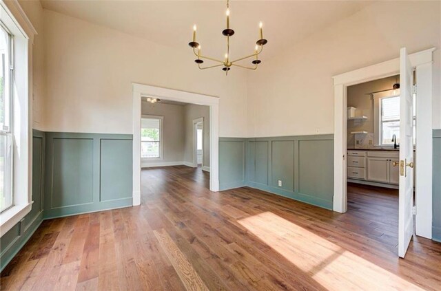 312 S Ash St, Guthrie, OK 73044 - unfurnished dining area with a decorative wall, a chandelier, wood finished floors, a wainscoted wall, and a sink