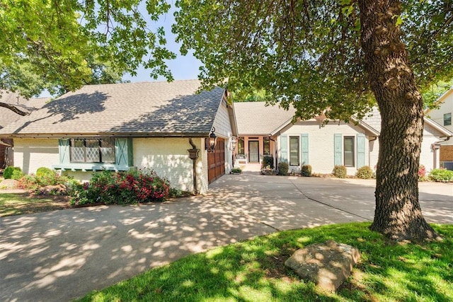 view of front facade featuring driveway, a garage, and roof with shingles