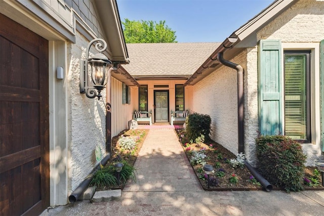 entrance to property with a porch, brick siding, and a shingled roof