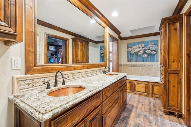 bathroom featuring wood finished floors, crown molding, a garden tub, double vanity, and recessed lighting