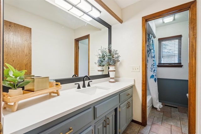 bathroom featuring vanity, stone tile floors, baseboards, and shower / bath combo