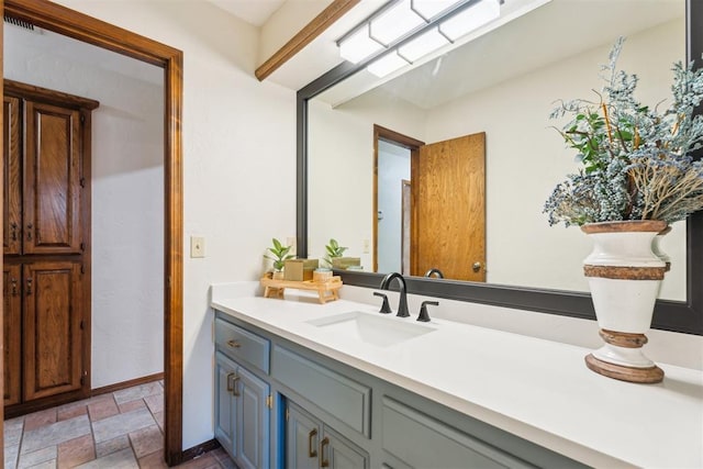 bathroom featuring stone finish flooring, vanity, and baseboards
