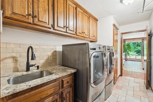 washroom featuring washing machine and dryer, cabinet space, and light stone finish flooring