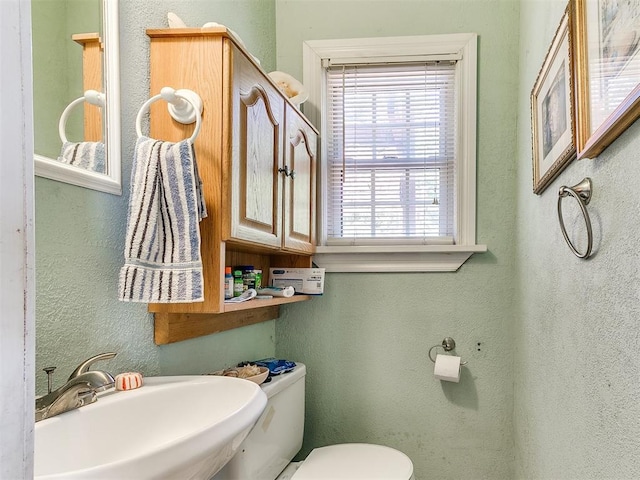 2321 Cashion Pl, Oklahoma City, OK 73112 - bathroom featuring a sink, toilet, and a textured wall