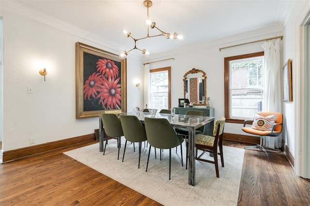 dining room featuring a chandelier, ornamental molding, wood finished floors, and baseboards