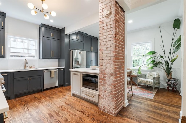 kitchen featuring stainless steel dishwasher, a sink, built in microwave, light wood finished floors, and crown molding