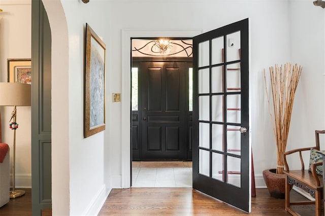 entryway with arched walkways, baseboards, and wood finished floors