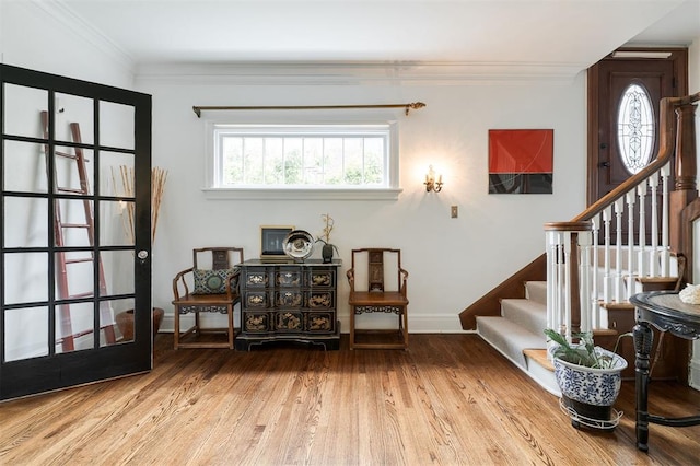 living area featuring stairs, crown molding, baseboards, and wood finished floors