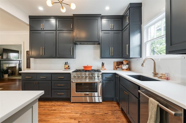 kitchen featuring stainless steel appliances, a sink, light countertops, recessed lighting, and wood finished floors