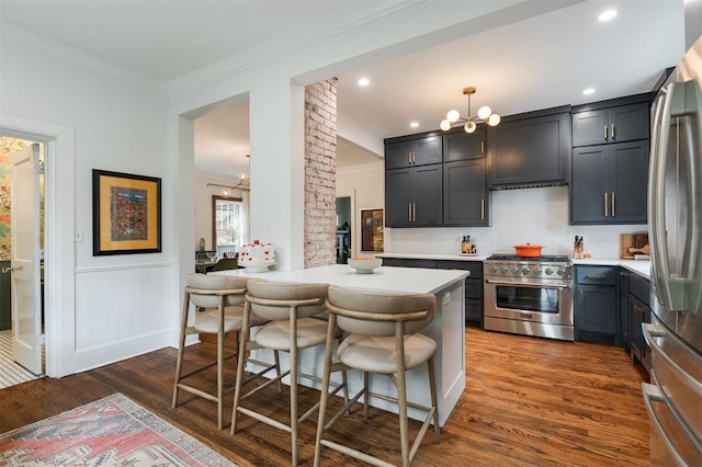 kitchen featuring stainless steel appliances, a chandelier, ornamental molding, dark wood-style floors, and light countertops