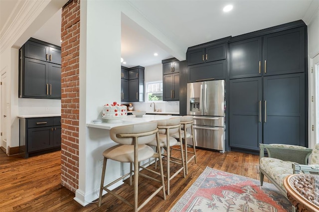 kitchen with stainless steel refrigerator with ice dispenser, a breakfast bar area, dark wood-type flooring, a peninsula, and recessed lighting