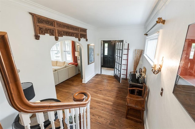 hallway featuring plenty of natural light, arched walkways, wood finished floors, ornamental molding, and baseboards
