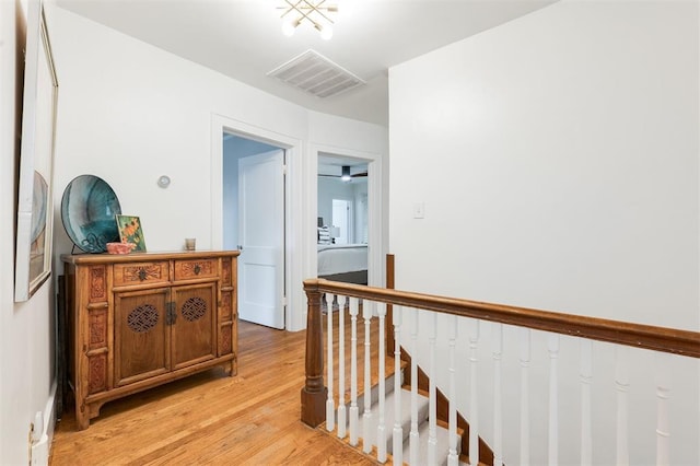 hallway with an upstairs landing and light wood-style flooring