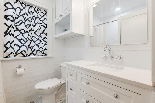 full bath with toilet, tile walls, vanity, and backsplash