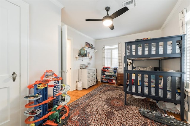 bedroom with crown molding, wood finished floors, and ceiling fan