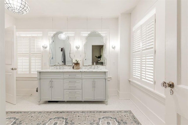 full bath with double vanity and baseboards