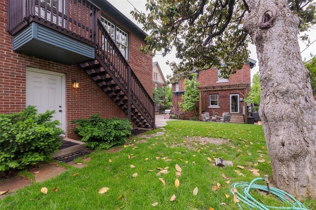 view of grassy yard featuring stairs and entry steps
