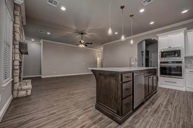 kitchen featuring stainless steel appliances, crown molding, a ceiling fan, arched walkways, and dark wood-style flooring