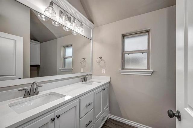 full bath featuring lofted ceiling, double vanity, baseboards, and wood finished floors