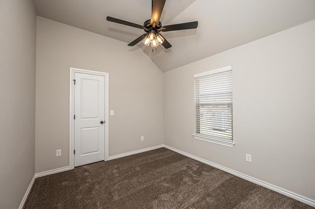 unfurnished room with a ceiling fan, vaulted ceiling, dark colored carpet, and baseboards